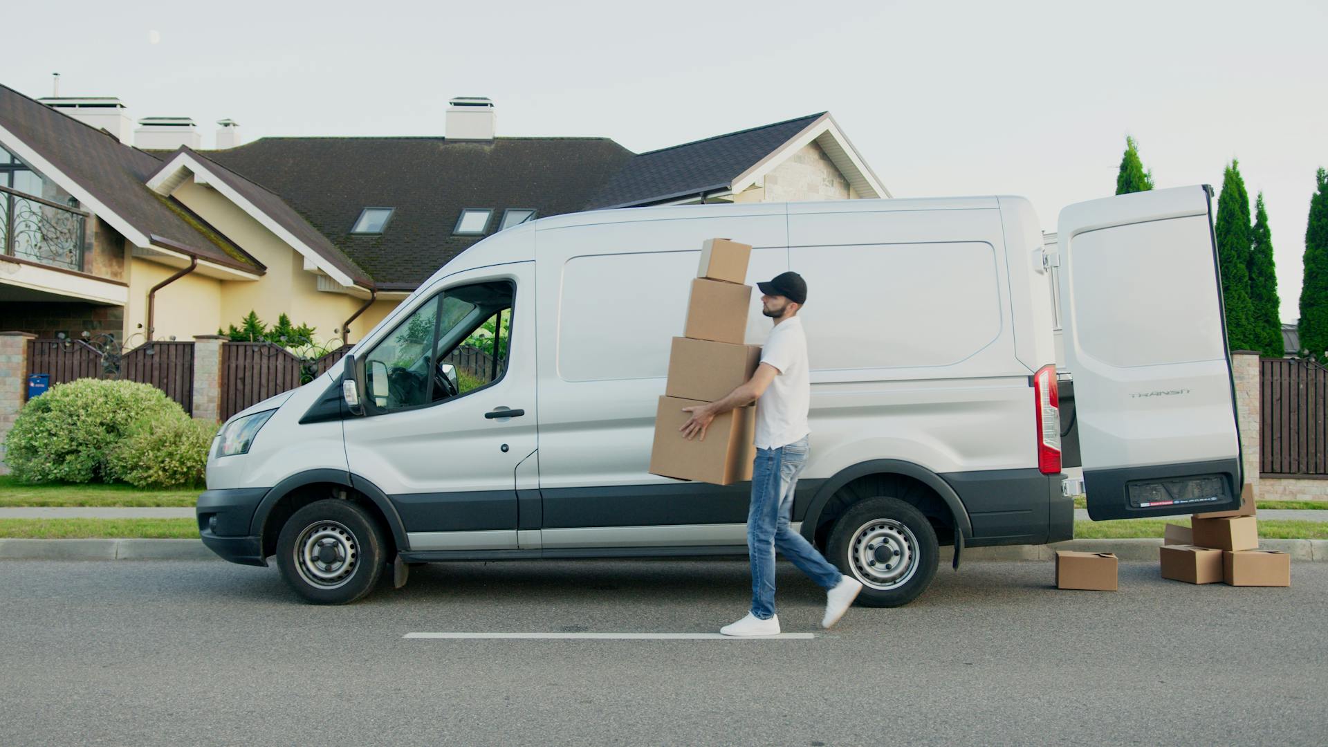 Man Carrying Boxes Beside a Van